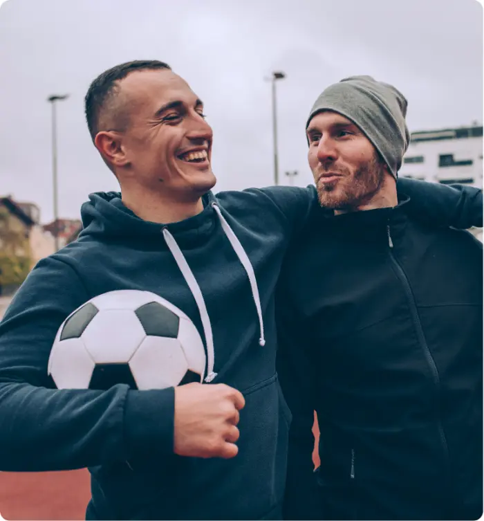 Two men smiling and supporting each other outdoors, representing healing, connection, and recovery through trauma treatment.