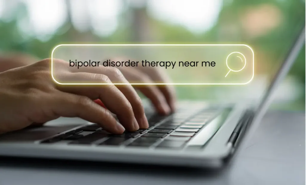 Hands typing on a laptop with a search bar displaying “bipolar disorder therapy near me,” symbolizing the search for mental health treatment.