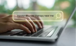 Hands typing on a laptop with a search bar displaying “bipolar disorder therapy near me,” symbolizing the search for mental health treatment.
