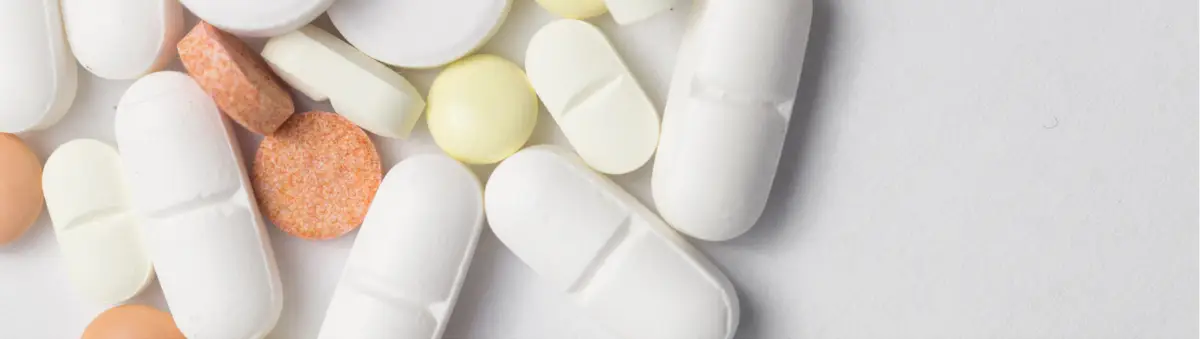 Close-up of assorted Prescription Medication and capsules on a light surface.