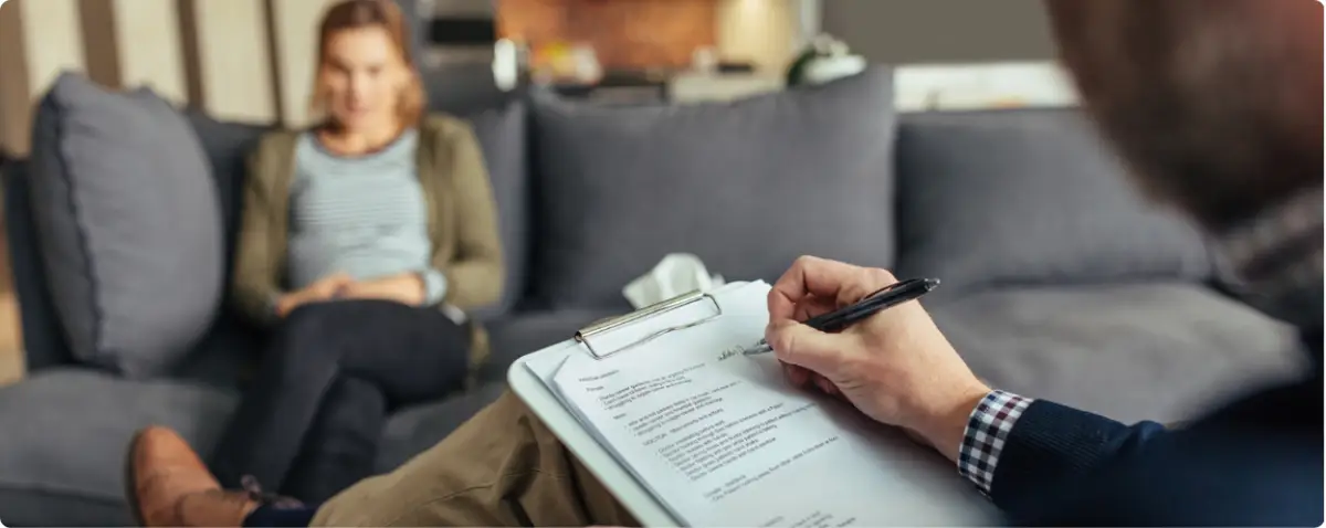 Therapist taking notes while counseling a woman for depression in a private therapy session