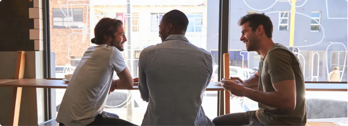 Men talking in supportive recovery community for trauma-informed addiction treatment.